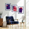A living room scene with a blue armchair, a wooden cabinet, and three abstract art pieces on the wall. Produktbild-Vorschau