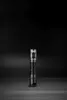 A black flashlight is centered on a black surface with a black background. Produktbild-Vorschau