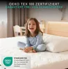 A young girl sitting on a mattress in a bedroom. Produktbild-Vorschau