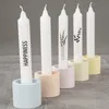 Five white candles are displayed in colorful concrete candle holders. Podgląd zdjęcia produktu