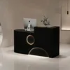 A black reception desk with a computer and a plant on it, in a modern interior. Produktbild-Vorschau