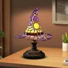 A witch hat-shaped stained glass table lamp sits on a wooden table. Produktbild-Vorschau
