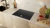 A modern kitchen countertop with an induction hob, sink, and various kitchen items. Anteprima dell’immagine prodotto