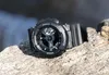 A black G-Shock watch rests on a textured rock surface with a blurred background of water and foliage. Produktbild-Vorschau
