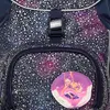 A close-up view of a backpack with a galaxy-like pattern and a decorative badge. Náhľad obrázku produktu