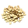 A pile of small, square, gold-colored tiles. Produktbild-Vorschau