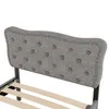 A close-up view of a gray upholstered headboard with tufting and nailhead trim, attached to a bed frame with wooden slats. Anteprima dell’immagine prodotto