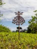 A solar-powered garden stake shaped like a fairy is planted in a grassy lawn with trees and a cloudy sky in the background. Produktbild-Vorschau