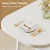 A close-up view of a glossy white tabletop with a place setting and a vase of flowers. Produktbild-Vorschau