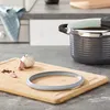 A kitchen counter scene with a cutting board, garlic, peppercorns, and a pressure cooker. Náhľad obrázku produktu