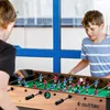 Two boys playing foosball in a room with a blue window frame. Náhľad obrázku produktu