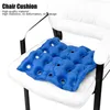 A blue inflatable chair cushion with air holes is placed on a white chair. Náhľad obrázku produktu