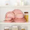 A set of pink and gold marbled dinnerware is displayed on a white shelf. Produktbild-Vorschau