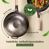 Two woks are shown, one in the foreground and one in the background with food. There are also leaf graphics. Produktbild-Vorschau