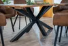 A close-up view of a dining table with a distinctive spider-leg metal base, surrounded by brown leather chairs. Produktbild-Vorschau