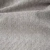 A close-up view of a light gray bouclé fabric. Produktbild-Vorschau