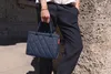 A person holding a small quilted handbag. Voir les images du produit