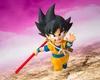 A Dragon Ball Z action figure of Son Goku as a child, holding a red staff, in a dynamic pose against a pink sky and rocky ground. Produktbild-Vorschau