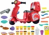 A collection of Play-Doh pizza-making accessories and tools arranged around a red toy scooter. Produktbild-Vorschau