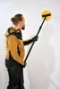 A man is using a sanding tool on a white wall. Podgląd zdjęcia produktu