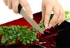Hands chopping green onions on a cutting board with red chili peppers. Náhled obrázku produktu