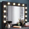 A vanity mirror with lights and makeup accessories on a dresser. Anteprima dell’immagine prodotto