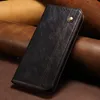 A black leather flip wallet phone case is shown against a background of rolled leather. Produktbild-Vorschau