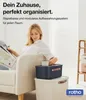 A woman is sitting on a sofa reading a magazine, with storage boxes next to her. Produktbild-Vorschau