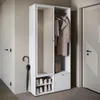 A modern hallway with a white wardrobe set, including a mirror, coat rack, shoe storage, and a drawer. An umbrella stands beside it, and a door is visible on the right. Anteprima dell’immagine prodotto