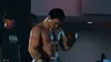 A boxer in boxing gloves looks down, with two other people in the background. Produktbild-Vorschau