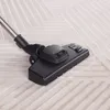 A close-up view of a vacuum cleaner head on a textured carpet. Produktbild-Vorschau
