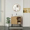A bathroom vanity with a round mirror above it, a plant to the side, and cabinets in the background. Produktbild-Vorschau