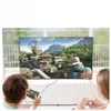 Two people are sitting in front of a TV, with one person holding a tablet connected to the TV via a cable. Produktbild-Vorschau