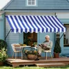 An elderly man sits on a patio reading a magazine under a blue and white striped awning. Náhled obrázku produktu