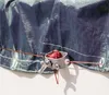 Close-up of a blue/black tarp with a red cord and a silver tensioning device. Produktbild-Vorschau