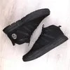 A pair of black mid-top sneakers on a light wooden floor. Voir les images du produit