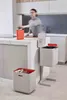 A person is sorting waste in a modern kitchen with two recycling bins. Podgląd zdjęcia produktu