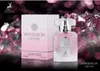 A perfume bottle and its box are displayed against a background of pink crystals and bokeh lights. Produktbild-Vorschau