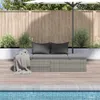 A grey rattan garden bed with dark grey cushions and a grey throw blanket is placed on a wooden deck next to a swimming pool. An umbrella is partially visible. Produktbild-Vorschau