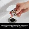 A hand is holding a sink drain stopper over a sink drain. Produktbild-Vorschau