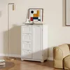 A white cabinet with drawers and a door stands in a room next to a floor lamp and a sofa. Náhled obrázku produktu