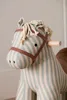 A close-up view of a striped rocking horse toy. Produktbild-Vorschau