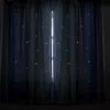 A close-up view of blue curtains with small white stars, illuminated from behind by a bright light source. Voir les images du produit