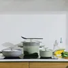 A set of sage green and gray pots and pans are arranged on a stovetop. Podgląd zdjęcia produktu