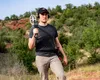 A man is holding a metal detector in a natural outdoor setting. Produktbild-Vorschau