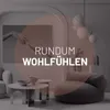 A modern living room scene with a large beanbag sofa and coffee tables, featuring a circular overlay with text. Náhľad obrázku produktu