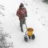 A person is using a spreader in the snow. Produktbild-Vorschau