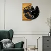 A wall clock with a mountain and forest scene is displayed on a light gray wall above a dark green armchair and a small side table. Voir les images du produit