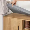 A hand is shown lifting a gray fabric lid from a wooden shoe cabinet. Produktbild-Vorschau
