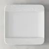 A white rectangular plate with textured edges, shown from a top-down view on a light gray textured surface. Produktbild-Vorschau